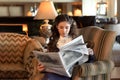 Marriageable girl is sitting in an old-fashioned armchair, dressed in a vintage velvet purple dress and reading a newspaper Royalty Free Stock Photo