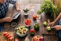 Married couple cooking together salad of vegetables on wooden ta Royalty Free Stock Photo