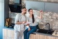 married couple with digital tablet looking away in kitchen smart