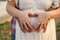 Married couple forming a heart shape with hands on the pregnant belly of the woman Royalty Free Stock Photo