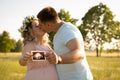 A married couple is holding an ultrasound scan showing their child