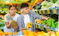 Married couple picks and buys bananas and pineapple in vegetable section of grocery supermarket Royalty Free Stock Photo