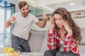 Married couple sitting on gray bed and arguing. Portrait of angry husband screams at crying disappointed wife during a Royalty Free Stock Photo