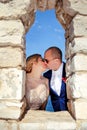 Married couple standing and kissing on the stone wall window Royalty Free Stock Photo