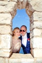 Married couple standing and posing on the stone wall window Royalty Free Stock Photo