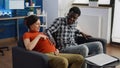 Married interracial couple expecting baby sitting on couch Royalty Free Stock Photo