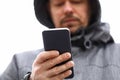 Married man in hood holds and looks at smartphone