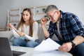 Married mature couple counting their expenses on laptop, reading papers, checking bills, planning finances Royalty Free Stock Photo