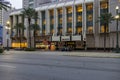 The Marriott Hotel on Canal Street with people standing outside, cars driving on the street, lush green palm trees