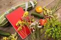 marrow squash, measure tape, blank red notepad, flowers, tomatoes and cucumbers on brown wooden table Royalty Free Stock Photo