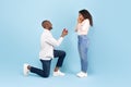 Marry me. Black middle aged man holding giving open box with engagement ring to excited young woman, side view Royalty Free Stock Photo