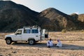 Marsa Alam, Egypt - November 10, 2020: Two men in traditional clothes are sitting near a touristic jeep in the desert