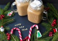 Marshmellou cocoa, Christmas tree ornaments and candy on a black background. The inscription Happy New Year