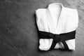 Martial arts uniform with black belt on grey stone background, top view. Space for text