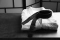 Martial arts uniform with black belt on grey stone table indoors