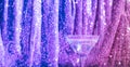 Martini cocktail on neon background of pink glittering curtain. Alcoholic classic drink with ice in an elegant glass Royalty Free Stock Photo