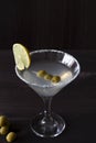 Martini glass with cocktail and olives on black background Royalty Free Stock Photo