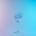 Martini glass with ice cubes in neon holographic vibrant pink and blue colors. Minimal celebration concept Royalty Free Stock Photo