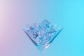 Martini glass with ice cubes in neon holographic vibrant pink and blue colors. Minimal celebration concept