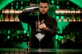 martini glass with ice and jigger stands on bar. Blurred bartender in background Royalty Free Stock Photo