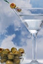 Martini glass with olives against cloudy ski on a wooden plank