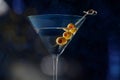 Martini, a glass with spicy olives, on a dark background. Alcoholic drink