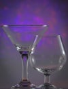 Martini Glass together with Cognac Glass with flashing bright violet lights on background