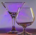 Martini Glass together with Cognac Glass with flashing smooth violet lights on background