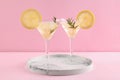 Martini glasses of cocktail with lemon slices and rosemary on marble tray against pink background Royalty Free Stock Photo