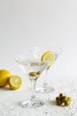 Martini with lemon. Two Martini glasses with cocktail and olives on white background Royalty Free Stock Photo