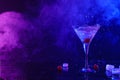 Martini splashing out of glass near ice and cherries in neon lights, space for text Royalty Free Stock Photo
