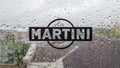 Martini sticker logo. A brand of Italian-made vermouths and sparkling wines. Water drop on glass window during rain with blurred Royalty Free Stock Photo