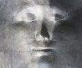 Black and white close-up image of woman`s face sculpted on metal. Distillery of