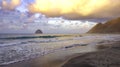 Tropical beach with waves and rocks with colourful evening clouds