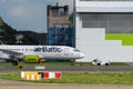 Marupe, Latvia - August 4, 2023 - An AirBaltic plane is being towed by a service car along the runway, the aircraft hangar in the