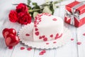 Marzipan white cake in the shape of a heart with red hearts. As the decoration bouquet of red roses a gift from the ribbon. Royalty Free Stock Photo