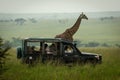 Masai giraffe stands by truck in grassland Royalty Free Stock Photo