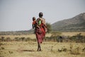 Masai Mara, Kenya - September 04, 2006: Masai tribal woman carrying her baby walking through the savanna