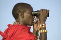 Masai scout with binoculars looks for animals during a tourist game drive at the Lewa Wildlife Conservancy in North Kenya, Africa