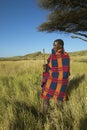 Masai Warrior in Senior Elder robe standing near Acacia Tree in Lewa Conservancy, Kenya Africa