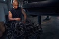 Masculine African American auto-mechanic standing near big black engine