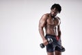 Masculine african guy with muscular sportive body holding dumbells on white background