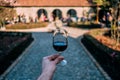 Masculine hand holding glass of Port Wine with winery and garden on the background, in Porto Portugal, city of the Port Wine Royalty Free Stock Photo