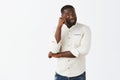Masculine handsome bearded African American male model in white shirt whipping teardrop from eye after watching dramatic