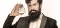 Masculine perfume, bearded man in a suit. Male holding up bottle of perfume. Closeup portrait. Perfume or cologne bottle