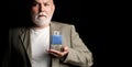 Masculine perfume, bearded old man in suit. Male holding up bottle of perfume. Aged man perfume, fragrance. Perfume or