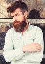 Masculinity concept. Guy looks suspicious. Hipster with tousled hair hold arms crossed on chest. Man with beard and Royalty Free Stock Photo