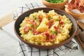 Mashed boiled potatoes. Bacon mashed potatoes with green onion, pepper and cheddar cheese in bowl on light old wooden backgrou