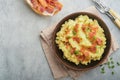 Mashed boiled potatoes. Bacon mashed potatoes with green onion, pepper and cheddar cheese in bowl on light old wooden backgrou