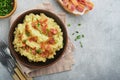 Mashed boiled potatoes. Bacon mashed potatoes with green onion, pepper and cheddar cheese in bowl on light old wooden backgrounds